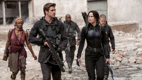 Gale Hawthorne (Liam Hemsworth) accompanies Katniss Everdeen (Jennifer Lawrence) as she sets out to film propaganda films as the symbol of the rebellion, The Mockingjay.