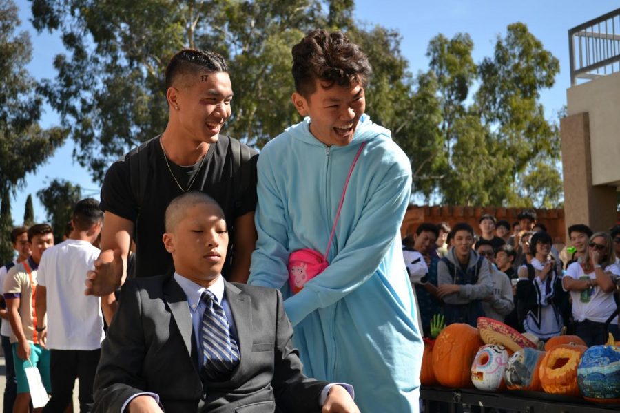 From left, juniors Ricky Kuo, Leo Lu wheel Christopher Lin, dressed as Professor X from the X-Men series, on Halloween.