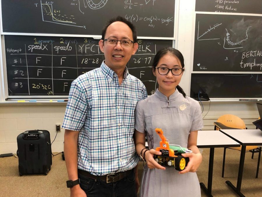 Du poses with the self-driving car she built at physics camp her junior year.